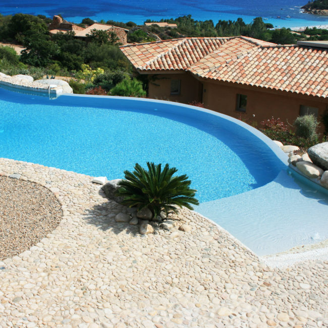 Piscine de forme libre avec débordement en Corse vert turquoise construction de piscine en béton armé
