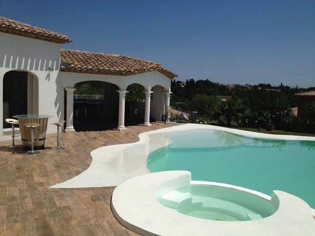 Bassin avec un spa en revêtement naturel beige piscine dans le 34 forme libre et beton armé revêtement couleur claire
