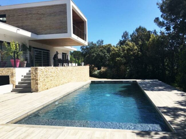 Une belle piscine contemporaine et design avec une maison type californienne